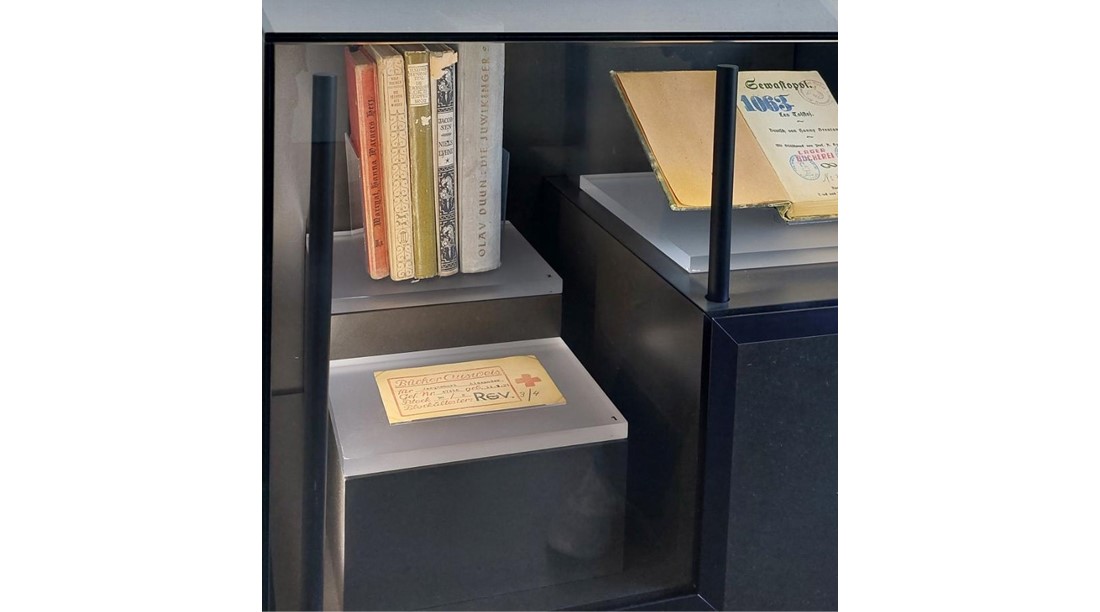 Bücher und Ausweis aus der Lagerbücherei des KZ Dachau in der Ausstellung der KZ-Gedenkstätte (Foto KZ-Gedenkstätte Dachau).