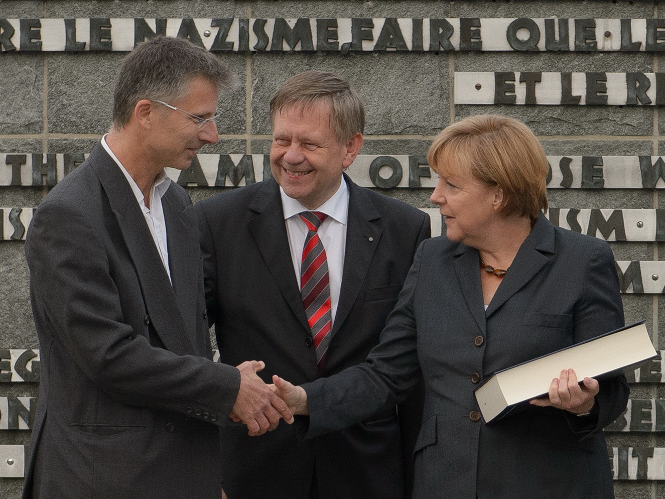 A. Knoll, K. Freller, Bundeskanzlerin a.D. A. Merkel (v.l.n.r.) mit Dachauer Totenbuch in Dachau, 2013. Foto: Stiftung Bayrische Gedenkstätten / KZ-Gedenkstätte Dachau